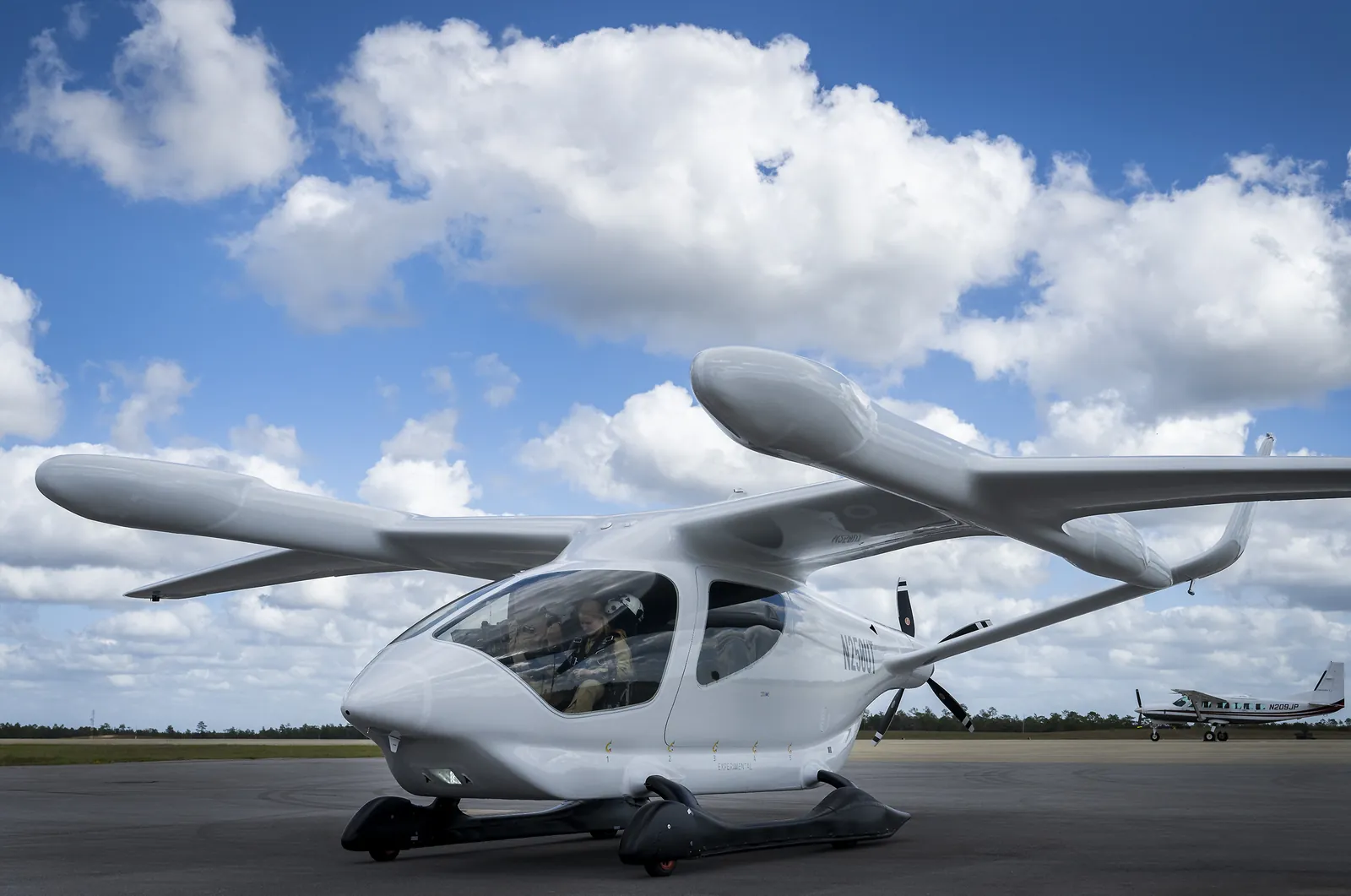 BETA electric aircraft on the airport ramp under a cloudy blue sky